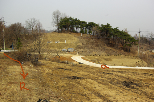  논산시 시유지 뒷편으로 통하는 신씨 문중 소유의 진입로(화살표 R)와 신씨 문중 소유 땅에 다른 사람이 묘지까지 낸 길(붉은 색 a). 주민들은 이미 도로부지를 내준 예를 들며 논산시 시유지 진입도로 또한 얼마든지 확보가 가능할 것이라고 입을 모으고 있다.